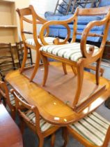 A yew wood extending dining table, and a set of six (4+2) chairs, in Regency striped material. The u