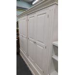 A white painted four door wardrobe with two drawers below.