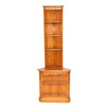An Ercol elm corner display unit, with a carved frieze over three small triangular shelves, above a