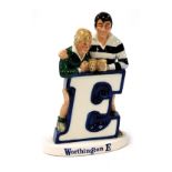 A Beswick Worthington E pottery advertising figure group, featuring two rugby players resting agains