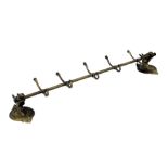 A brass wall hanging coat rack, the wall mounts formed as horse's head, on a circular and leaf cast