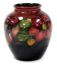 A Moorcroft Flambe pottery Clematis pattern vase, decorated on a red to blue ground, painted mark an