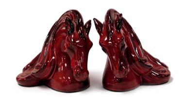 A pair of Flambe pottery bookends, modelled as horse's head, with swirling manes, 19cm high.