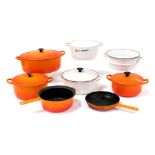 A Le Creuset white enamel steamer, orange enamel casserole dish, two further stewing pots and covers