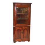 A Victorian mahogany corner display cabinet, the outswept pediment over an arched glazed door enclos