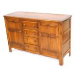 An Ercol elm sideboard, with four central drawers flanked by a pair of panelled doors, raised on sti