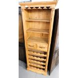 A pine wine cupboard chest, with three shelves over two drawers, above a series of wine bottle racks