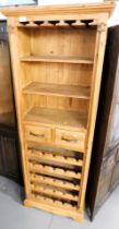 A pine wine cupboard chest, with three shelves over two drawers, above a series of wine bottle racks