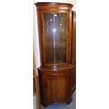 A mahogany corner display cabinet, with glazed door over solid door, raised on bracket supports.