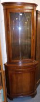 A mahogany corner display cabinet, with glazed door over solid door, raised on bracket supports.