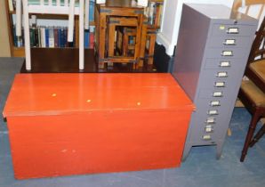 A grey filing cabinet, and a red painted blanket box.