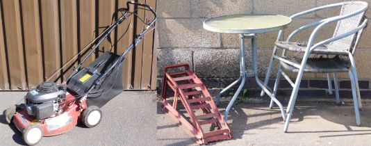 A circular metal and glass garden table and two chairs, a Mountfield petrol lawn mower, with Honda G