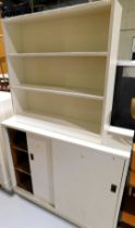 A white painted bookcase of three shelves, and a cupboard of two sliding doors, along with a small d