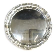 A George V silver salver, of circular form with piecrust border, raised on three scroll cast feet,