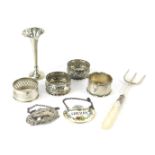 A group of small silver, to include four napkin rings, of differing form, a decanter label for gin,