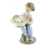 A Lladro porcelain figure, modelled as a seated girl holding upturned hat containing birds, printed
