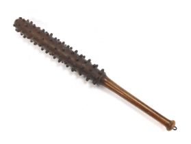 A World War One wooden trench club, the tapering handle joining a cylindrical club with various rais