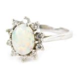 An opal and diamond dress ring, formed as a cluster with central oval opal in claw setting, surround