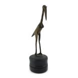 A 20thC bronze sculpture, modelled as a stork, with incised decoration, mounted on an ebonised cylin