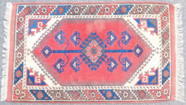 An Eastern rug, on a red and blue ground, with central medallion and tassel ends, 123cm x 75cm.