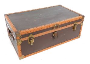 An early 20thC brown and tan leather bound trunk, with brass fittings, named to the lid for M. Dobne