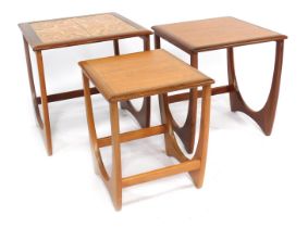 A nest of three G-Plan teak tables, each with a tiled top, raised on U shaped supports, largest 49cm