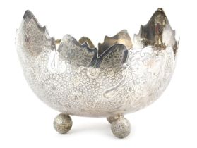 A Burmese white metal bowl, with shaped edge, the bowl decorated with leaves, flowers, etc., on thre
