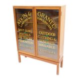 A teak two door display cabinet, with applied advertising for Atkin and Vrant Ltd Clothing and Gun s