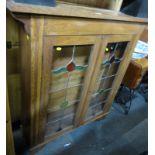 An early 20thC oak cabinet, of two glazed leaded doors, 116cm high, 107cm wide, 28cm deep.