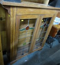 An early 20thC oak cabinet, of two glazed leaded doors, 116cm high, 107cm wide, 28cm deep.