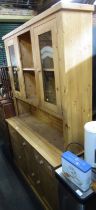 A pine kitchen dresser, the top with two recessed flanked by two glazed fronted doors, the base with
