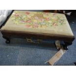 A mahogany footstool, with embroidered top, raised on ball and claw feet, 80cm wide.