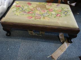 A mahogany footstool, with embroidered top, raised on ball and claw feet, 80cm wide.