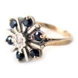 A sapphire and diamond cluster ring, set in white metal, with central diamond approx 0.05ct, flanked