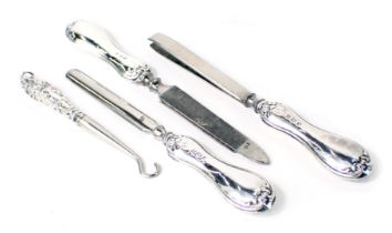 Four silver handled manicure implements, comprising two files, tweezers, and a button hook.