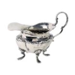 A late Victorian small silver cream jug, of lobed form, with four scroll shaped feet, Sheffield 1899