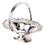 A George V silver basket, of fluted design with pierced floral border and swing handle, on oval foot