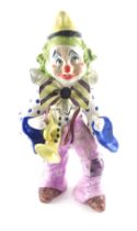 A large Italian pottery figure of a clown, with trumpet, etc., 55cm wide. (AF)