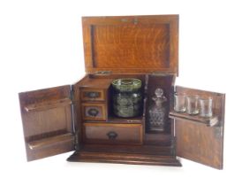 An early 20thC oak smoker's cabinet, with hinged lid and doors, enclosing three drawers, pipe rack,