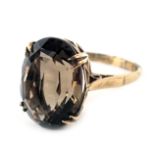 A 9ct gold smoky quartz dress ring, the oval smoky quartz in four double claw setting, in a raised b