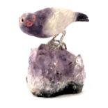 A quartz and amethyst carved bird, the bird perched on a rock with white metal mounts, 7cm high.