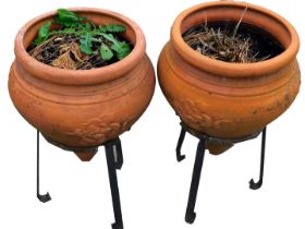 A pair of terracotta urn planters, each on metal stand, with rose detail, 66cm high, 35cm diameter.