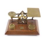 A set of early 20thC brass and oak letter scales, stamped Inland Letter Post, with some weights.