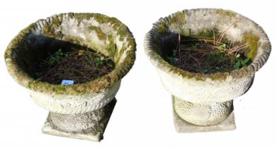 A pair of reconstituted stone garden urns, each with berry and vine detail on a square foot, 32cm hi