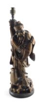 A late 19th/early 20thC Chinese carved lamp base, modelled in the form of a gentleman holding a fish