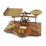 A set of brass and oak postal scales, with ivorine plaque and some weights.