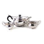 A George V silver three piece tea service, with shell capped beaded border, with fluted bodies, comp