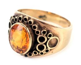 A 9ct gold Arts and Crafts style dress ring, with central oval cut citrine, in rub over setting, wit