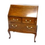 An oak bureau, the fall enclosing a fitted interior above two short and one long drawer with brass d