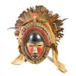 An African tribal Big Dan warrior mask, embellished with horns, shells, etc., with black, cream and